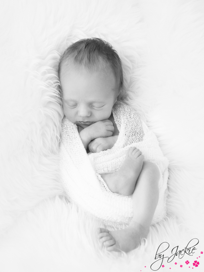 Monochrome image of newborn baby boy wrapped in blanket and fast asleep. Babies By Jackie near York