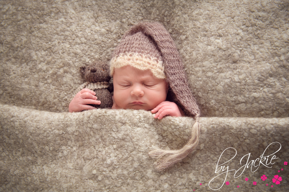 Photograph of a baby boy snuggling his teddy wearing a night cap. Image by Babies By Jackie, specialist baby photographer in Yorkshire, UK