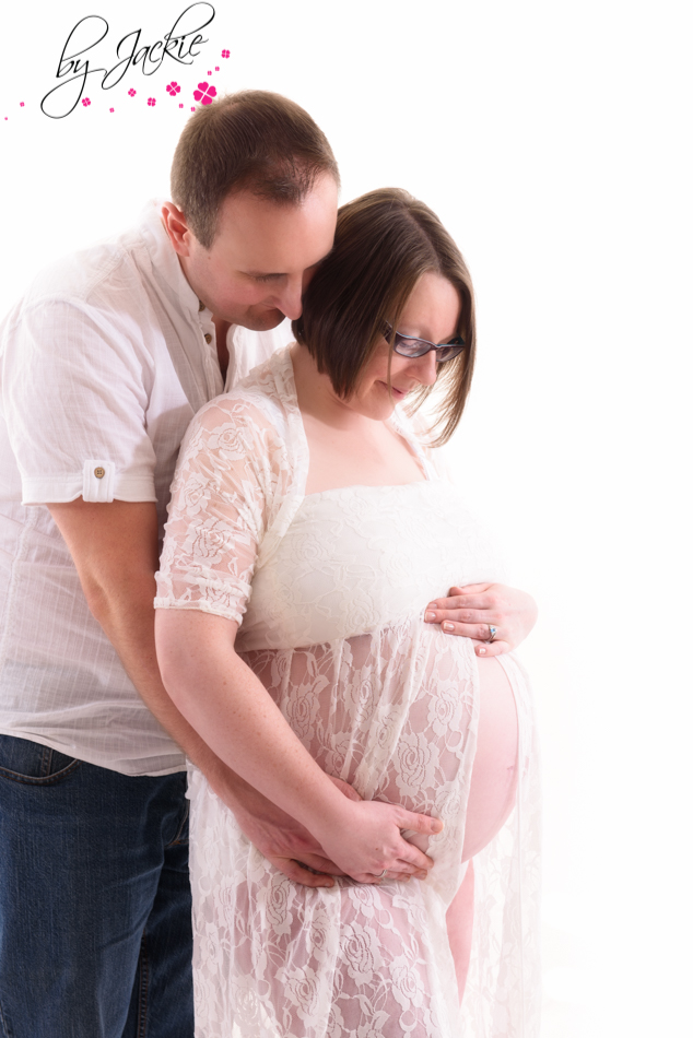 Couple posing for maternity photo, man cuddling wife looking at bump, image by Babies By Jackie near Howden, UK